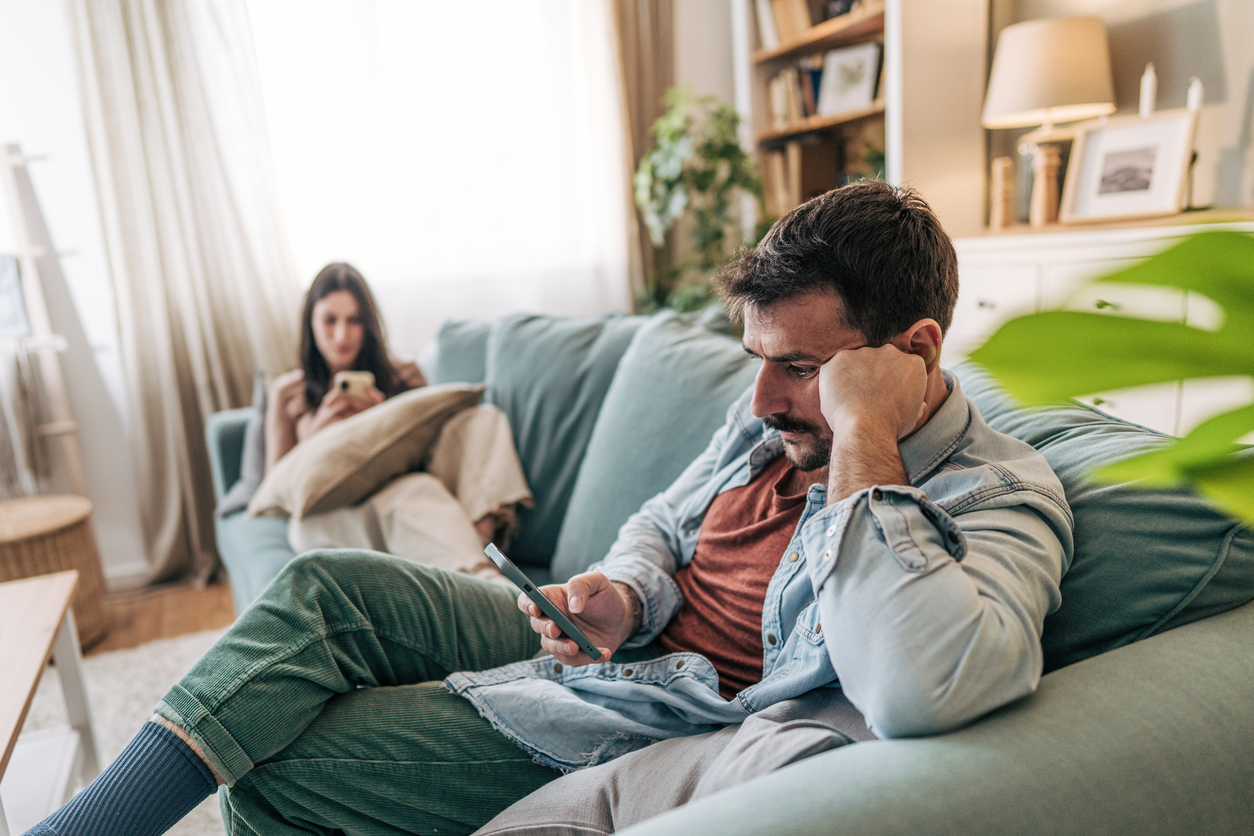 Couple Experiencing Communication Issues While Using Smartphones On Sofa